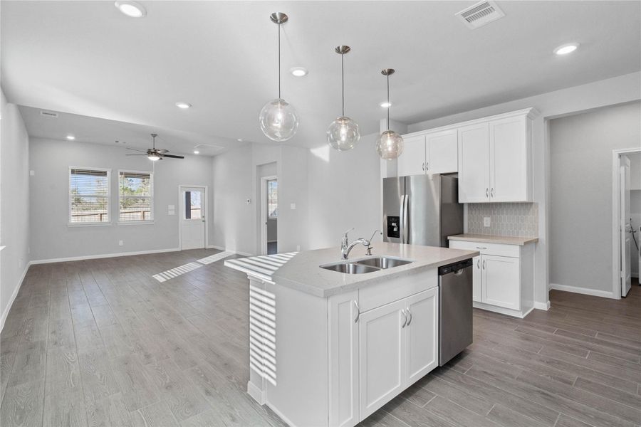 As you step past the entryway, you are immediately welcomed by a bright, open-concept kitchen that serves as the home's focal point. The space feels clean and modern, anchored by a large quartz-topped island that seamlessly connects the cooking area to a long, light-filled living space.