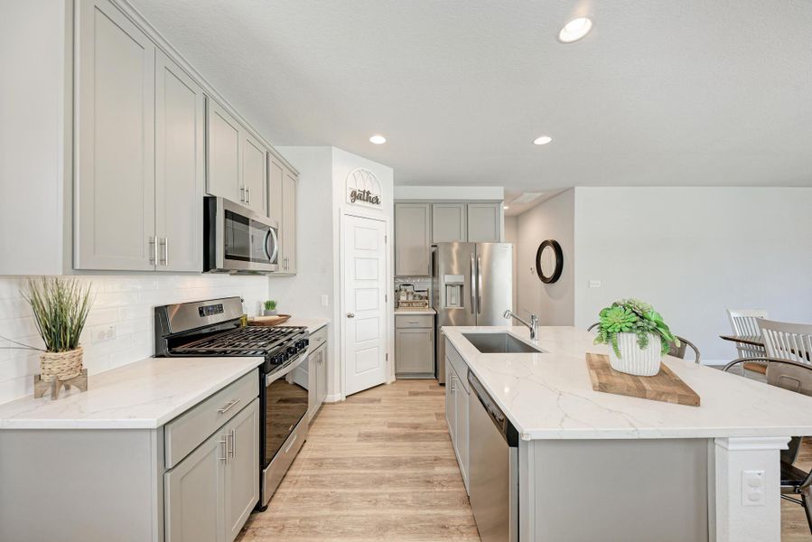 Kitchen featuring stainless steel appliances, backsplash, recessed lighting, light stone counters, and light wood-type flooring