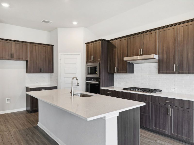 This kitchen features slate-colored cabinets and quartz countertops.