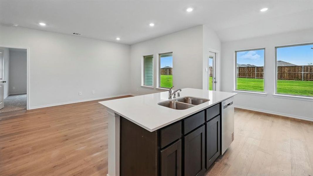 Kitchen with an island with sink, light wood-style floors, open floor plan, recessed lighting, and light stone counters