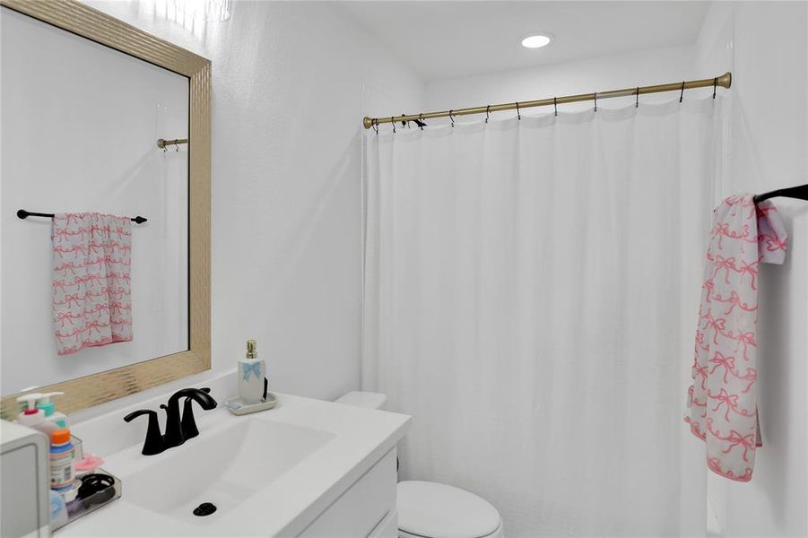 Bathroom featuring a single vanity with an integrated sink, matte black faucet, and a framed mirror