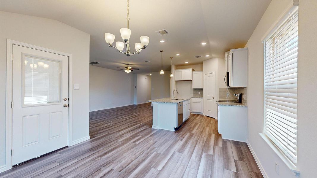 Kitchen with suspended lighting, open floor plan, a ceiling fan, light stone countertops, and white cabinets Kitchen with suspended lighting, open floor plan, a ceiling fan, light stone countertops, and white cabinets