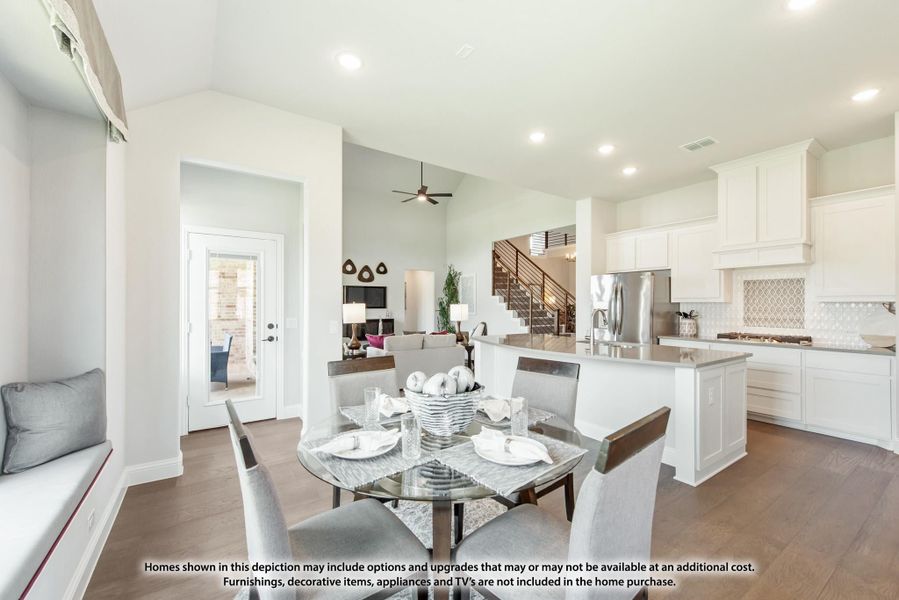 Open-concept dining area with round glass table, connected to white kitchen with island and hardwood floors