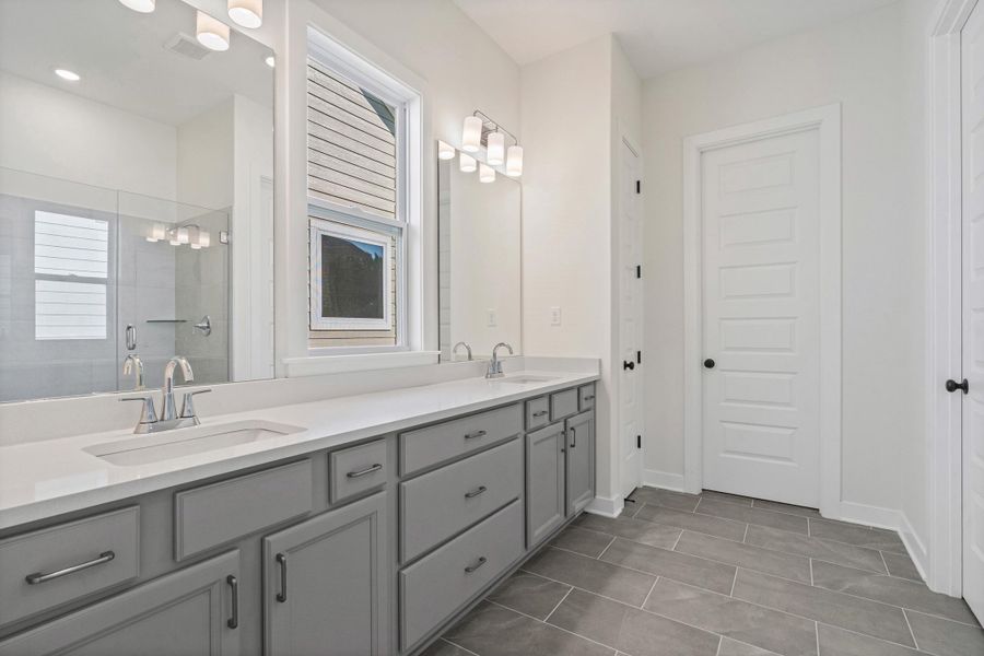 Dual vanity with light gray cabinetry, chrome hardware, white countertops, and integrated sinks