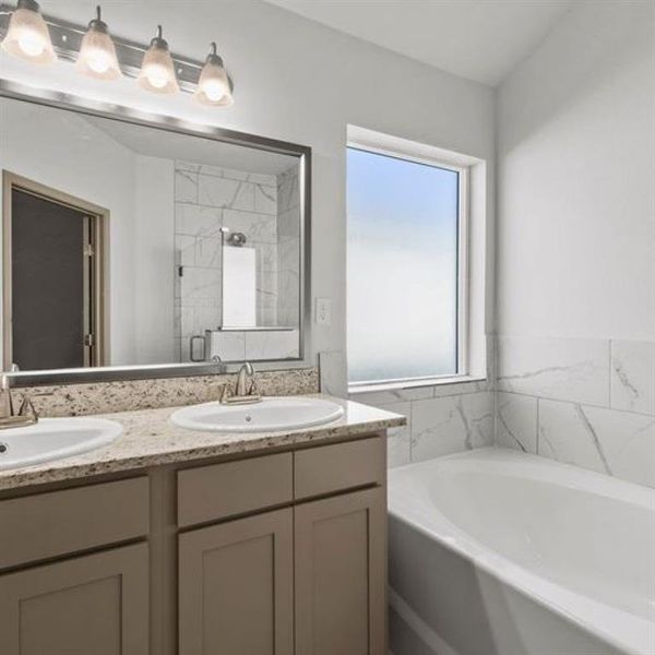 The primary bath feature dual sinks with large vanity, large soaking tub and glass framed standing shower. **This image is from another Saratoga Home with similar floor plan - Myrtle Floorplan.**