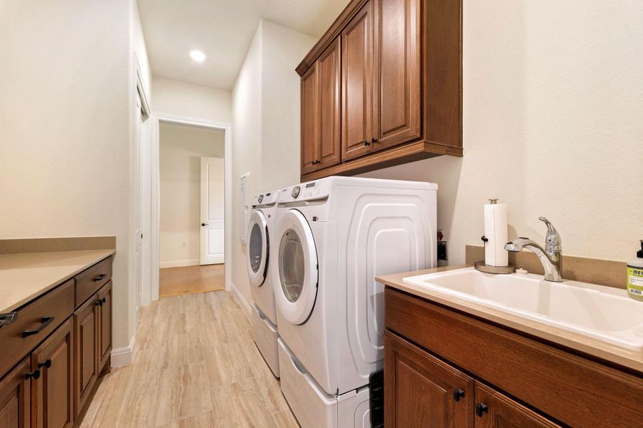Functional laundry space featuring modern appliances, ample storage cabinetry, and a convenient utility sink. Functional laundry space featuring modern appliances, ample storage cabinetry, and a convenient utility sink.