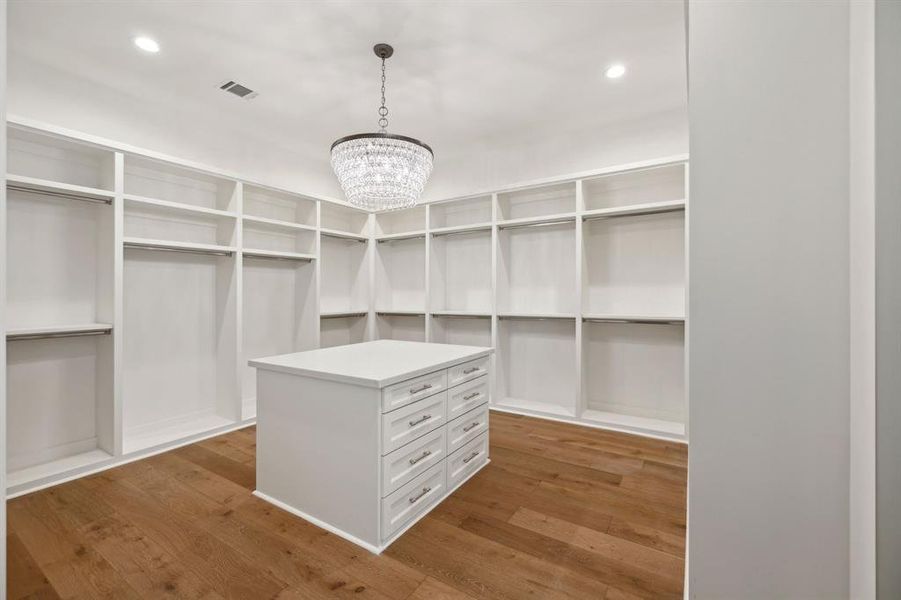 Oversized walk-in primary closet with packing island offering incredible storage.