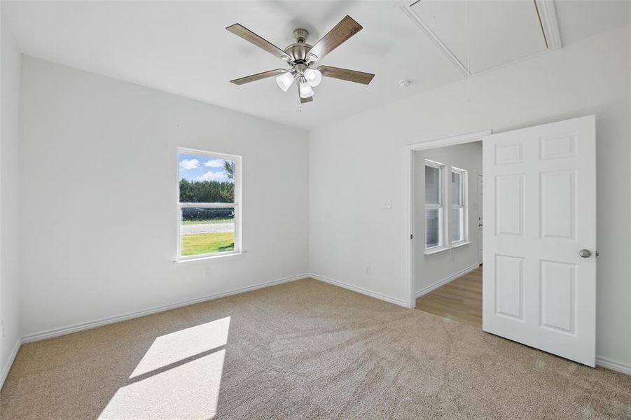 Carpeted empty room featuring attic access, ceiling fan, baseboards, and a smoke detector Carpeted empty room featuring attic access, ceiling fan, baseboards, and a smoke detector