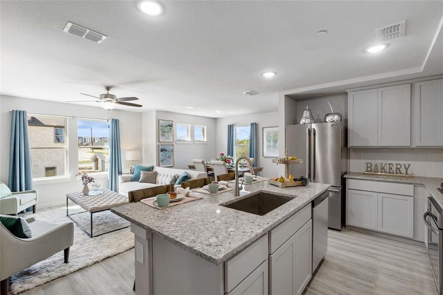 Kitchen featuring light hardwood / wood-style floors, an island with sink, stainless steel appliances, sink, and ceiling fan