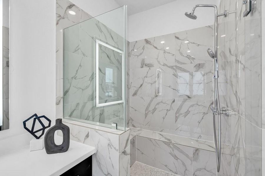 Similar plan and finishes with large walk in shower with frameless shower door and bench seat.