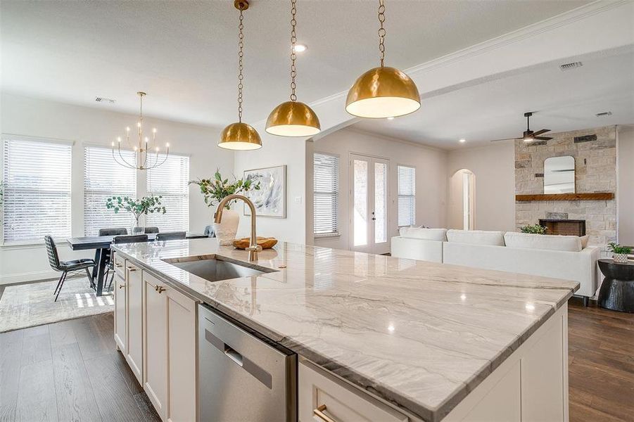 Kitchen featuring a large island, Quartzite countertops, gold hardware, decorative light fixtures, custom cabinetry to the ceiling, gas cooktop, double oven and walk in pantry