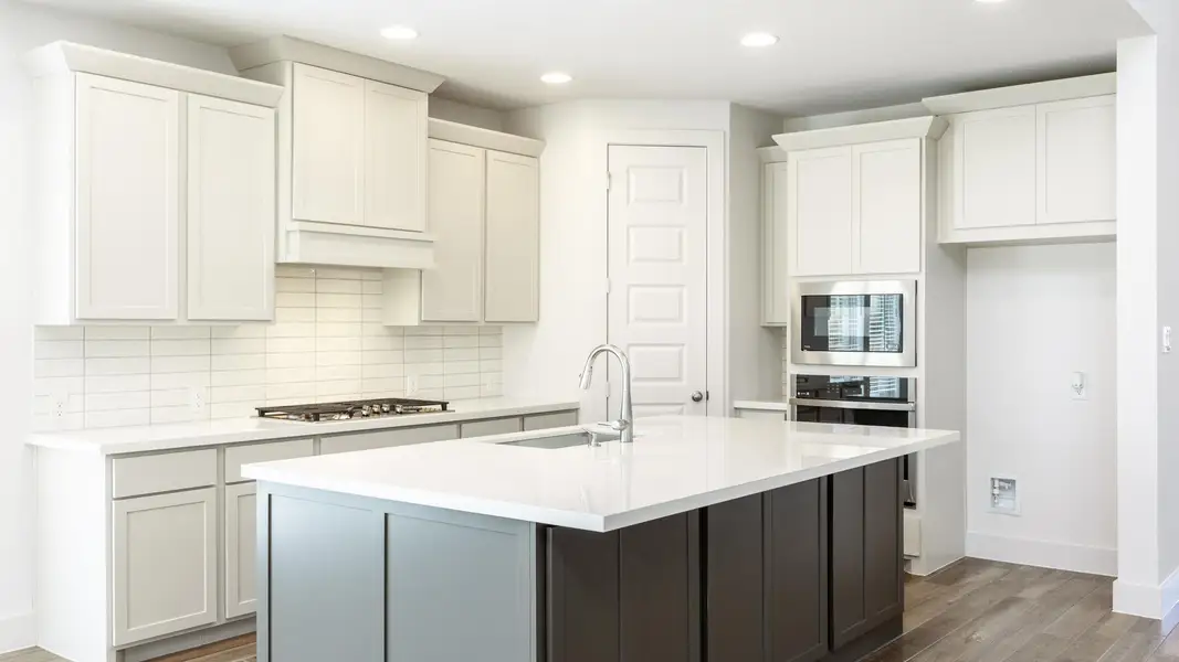 Kitchen featuring tasteful backsplash, wood finished floors, appliances with stainless steel finishes, recessed lighting, and an island with sink