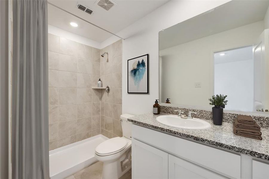 Bathroom with vanity, toilet, and tiled shower