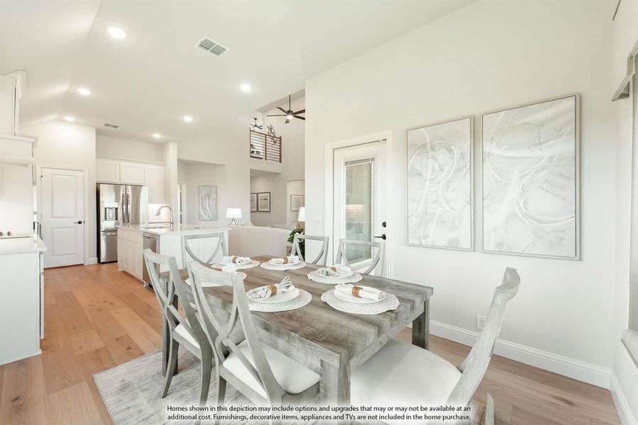 Dining area with wood table, six chairs, and hardwood floors open to kitchen with white cabinets and stainless appliances
