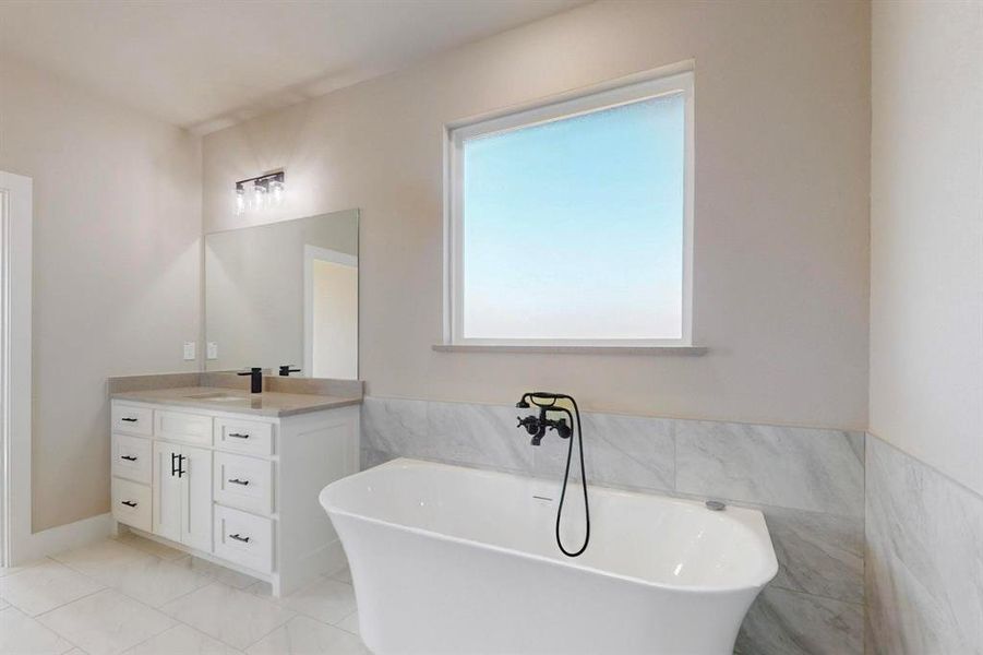 Bathroom featuring vanity, tile walls, a freestanding tub, and marble finish floor