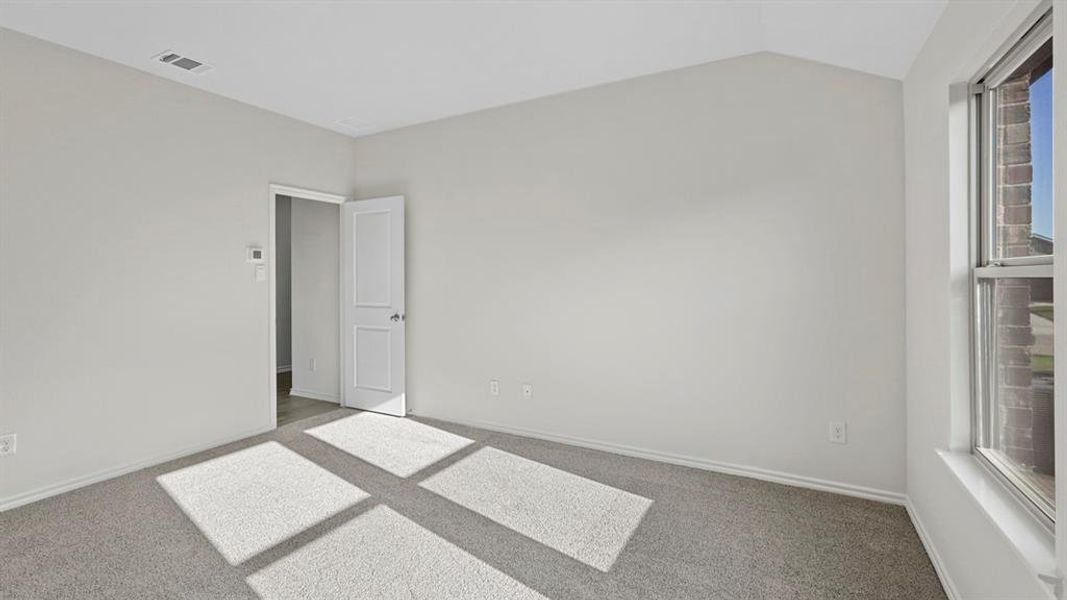 Carpeted spare room featuring lofted ceiling and baseboards