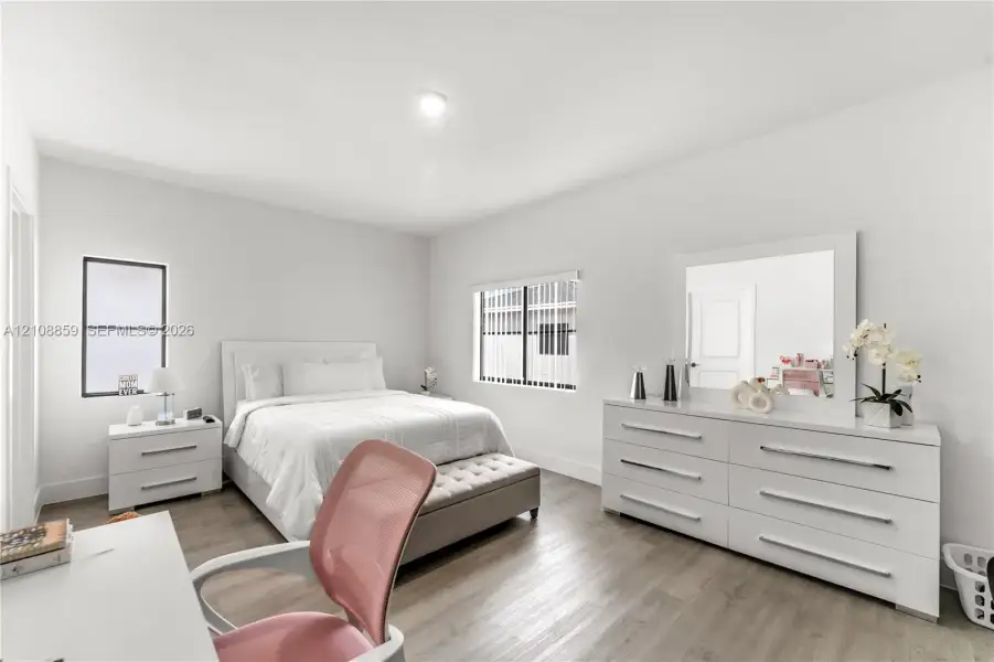 Neutral interior space featuring wood-finish flooring, crisp white walls, dual windows, and recessed ceiling lighting