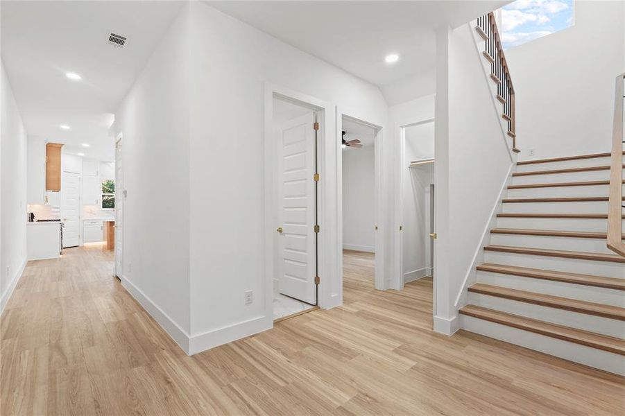Hallway featuring plenty of natural light, stairs, recessed lighting, and light wood-type flooring