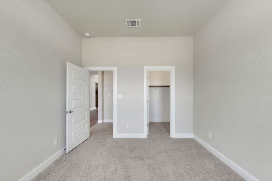 Unfurnished bedroom featuring carpet floors and a walk in closet Unfurnished bedroom featuring carpet floors and a walk in closet