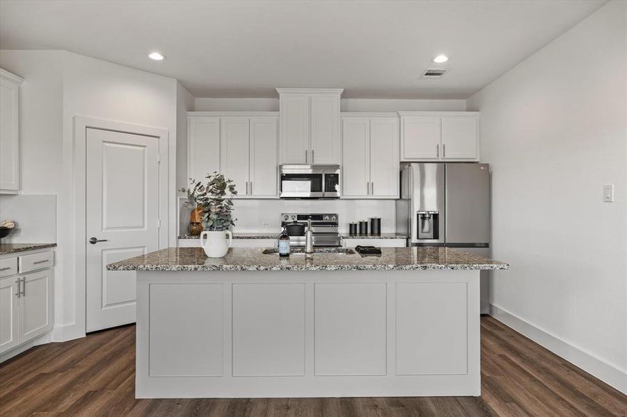 Kitchen with white cabinets, dark hardwood / wood-style floors, stainless steel appliances, and an island with sink