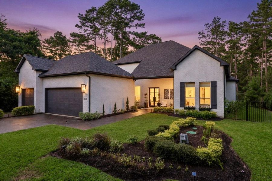 Stunning modern farmhouse curb appeal welcomes you home with a timeless white brick exterior, rich black accents, and beautifully landscaped grounds. A charming covered front porch creates the perfect place to relax, while the oversized driveway and spacious 3-car garage provide ample parking and storage. Thoughtfully designed landscaping, mature trees, and elegant exterior lighting enhance the home’s striking presence. Nestled on a private wooded homesite in a gated community!