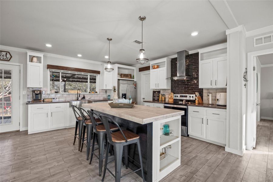 Kitchen with open shelves, a breakfast bar, stainless steel appliances, white cabinetry, and crown molding