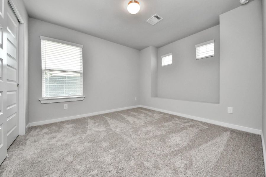 Secondary bedroom features plush carpeting, large windows that let in plenty of natural light, bright paint, and spacious closets. Sample photo of completed home with similar floor plan. Actual colors and selections may vary.