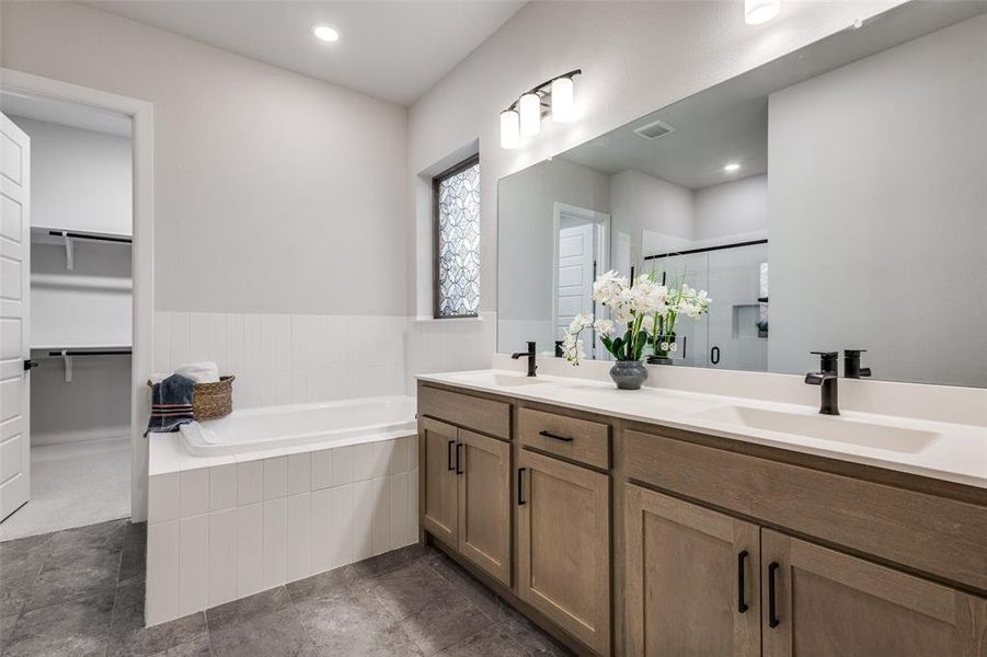 Bathroom with double vanity, a spacious closet, a stall shower, a bath, and recessed lighting