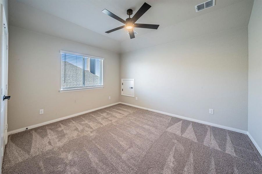 Spacious room featuring neutral carpeting, a large window with blinds, a contemporary ceiling fan with integrated lighting, a ceiling vent, and a flush-mounted access panel