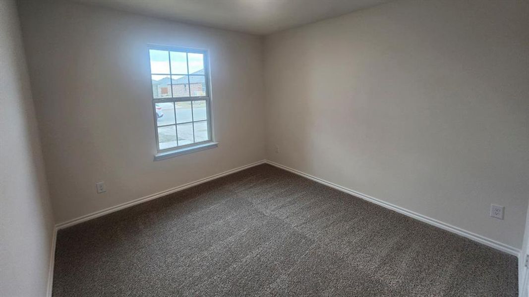 Spacious room featuring neutral paint, gray carpet, white baseboards, and a double-paned window with grid inserts
