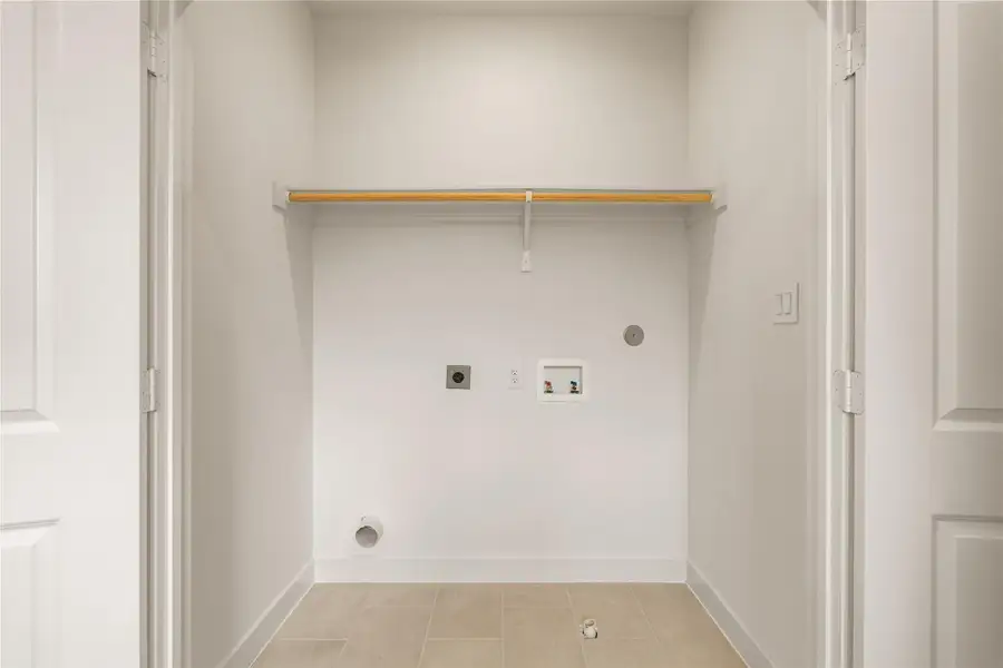 Upper-level laundry nook — dedicated tiled closet space equipped with built-in storage shelf and hanging clothes rod.