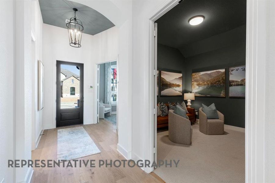Entryway with wood finished floors and a chandelier