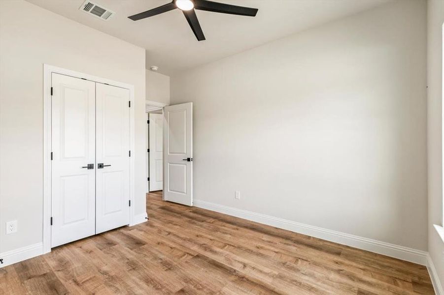 Room featuring wood-finish flooring, white walls, and a ceiling fan with integrated lighting