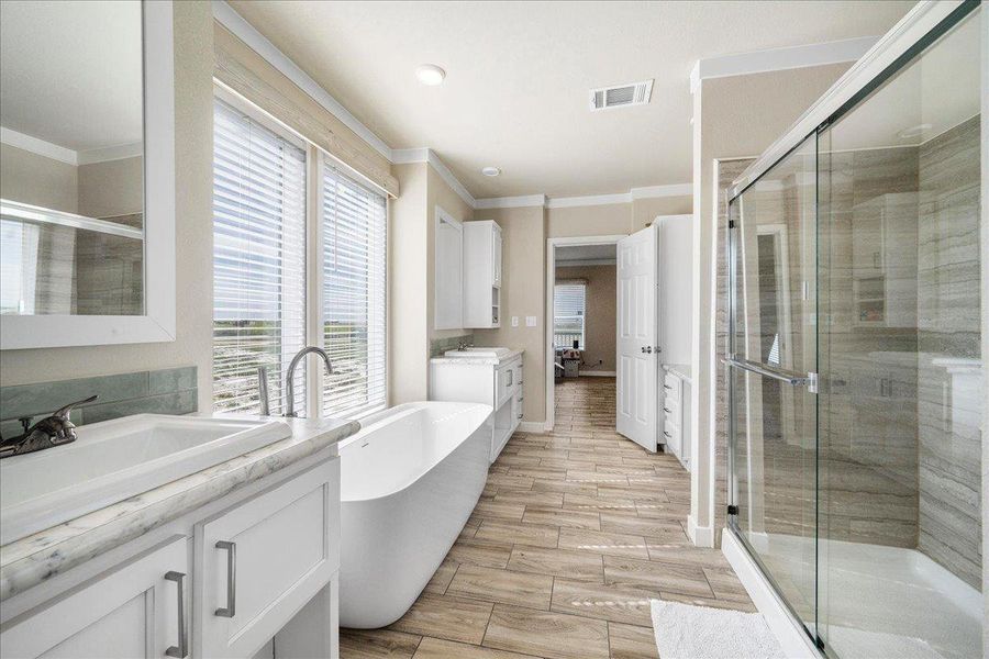Full bathroom featuring two vanities, wood finish floors, ornamental molding, a soaking tub, and ensuite bathroom Full bathroom featuring two vanities, wood finish floors, ornamental molding, a soaking tub, and ensuite bathroom
