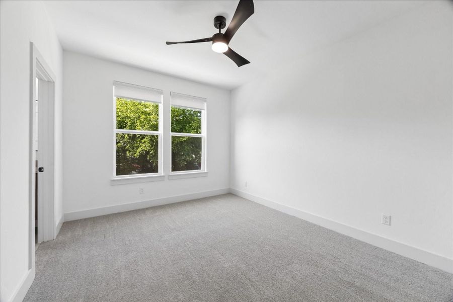 Spacious secondary bedroom offers a bright and versatile layout, making it ideal for family, guests, or a home office. Large windows fill the room with natural light while providing peaceful treetop views. Plush carpeting, recessed lighting, a modern ceiling fan, and generous wall space create a comfortable retreat that is ready to personalize to fit your lifestyle.