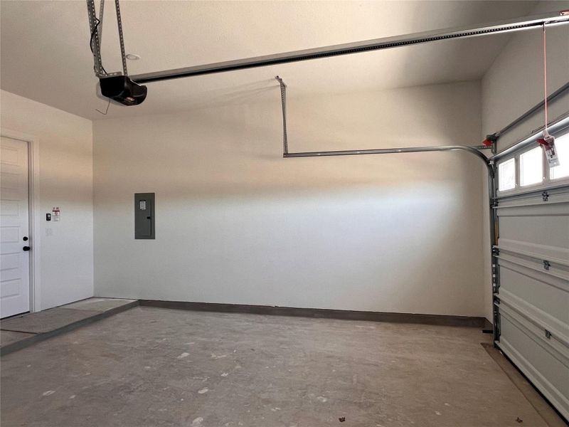 Garage featuring electric panel and a garage door opener