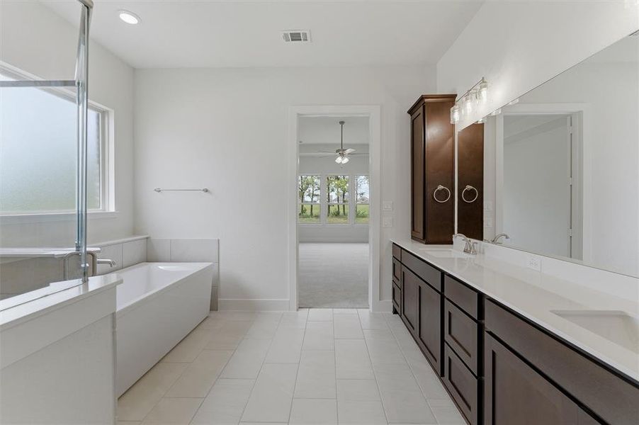 Contemporary bathroom featuring an elongated soaking tub, a double vanity with integrated sinks, and white tile flooring