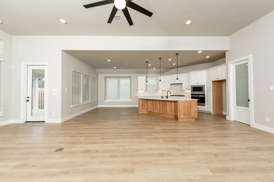 The dining area is filled with natural light and features high ceilings, recessed lighting, and expansive windows. The access door seamlessly connects the indoor living space to a covered patio for effortless year-round entertainment.