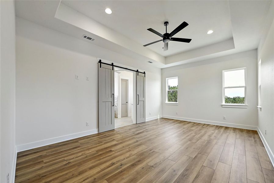 Large master bedroom with vinyl plank flooring and barn doors leading to the master bath. Ceiling fans in all the bedrooms.