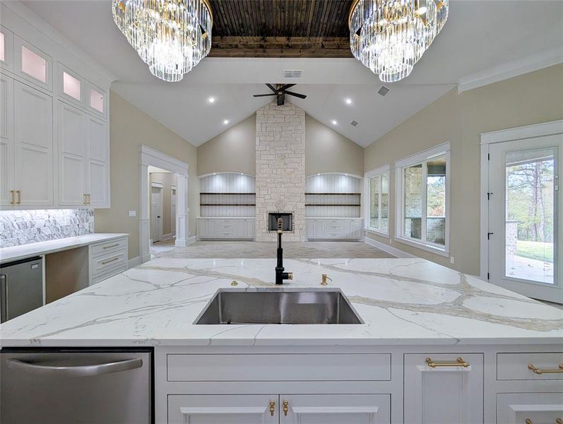 Kitchen with a chandelier, white cabinets, light stone countertops, and ceiling fan