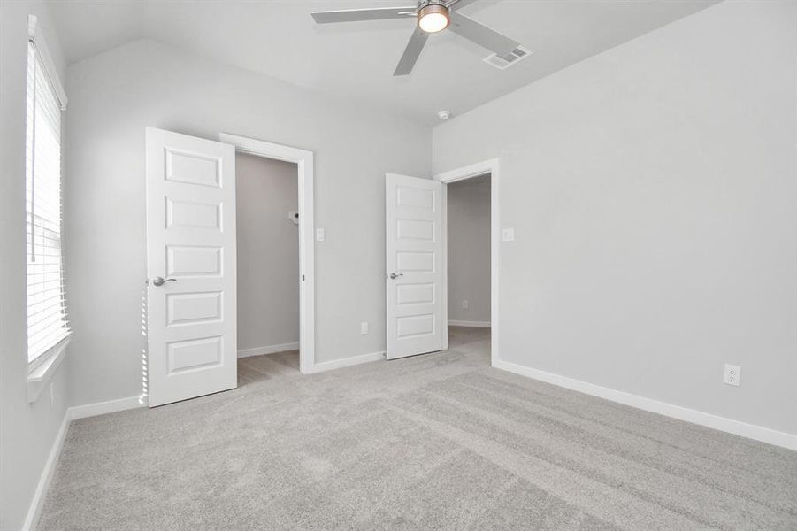 Secondary bedroom features plush carpeting, large windows that let in plenty of natural light, bright paint, and spacious closets.