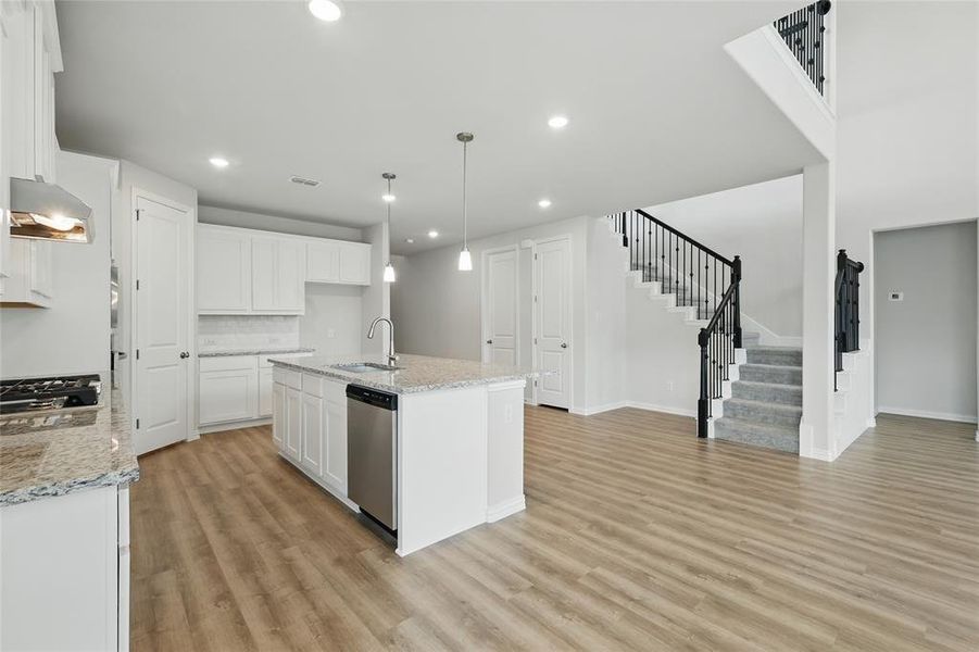 Kitchen with appliances with stainless steel finishes, a sink, light wood-type flooring, white cabinets, and recessed lighting Kitchen with appliances with stainless steel finishes, a sink, light wood-type flooring, white cabinets, and recessed lighting