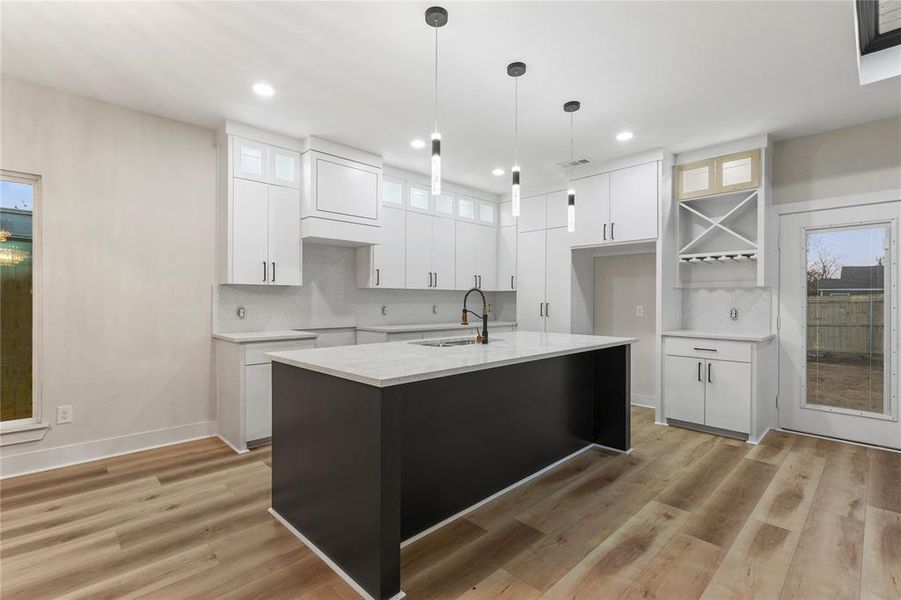 Kitchen with white cabinetry, glass insert cabinets, decorative backsplash, an island with sink, and recessed lighting