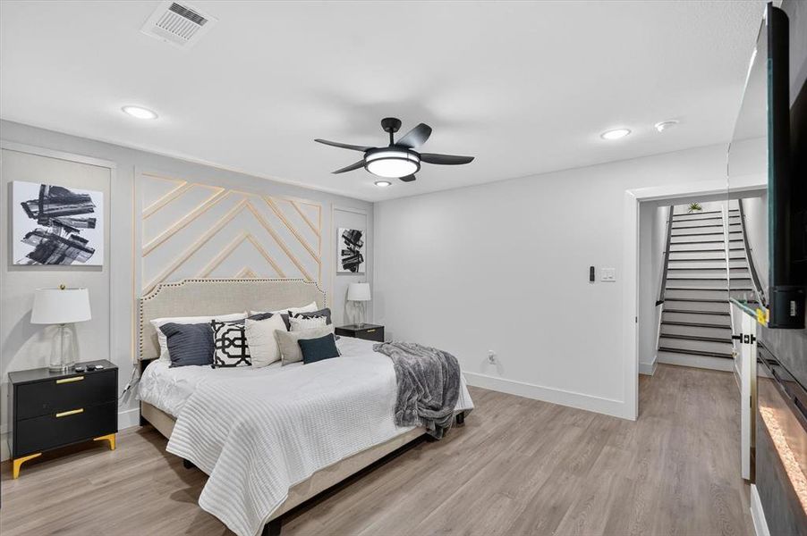 Bedroom featuring a decorative accent wall, recessed lighting, and wood-finish flooring