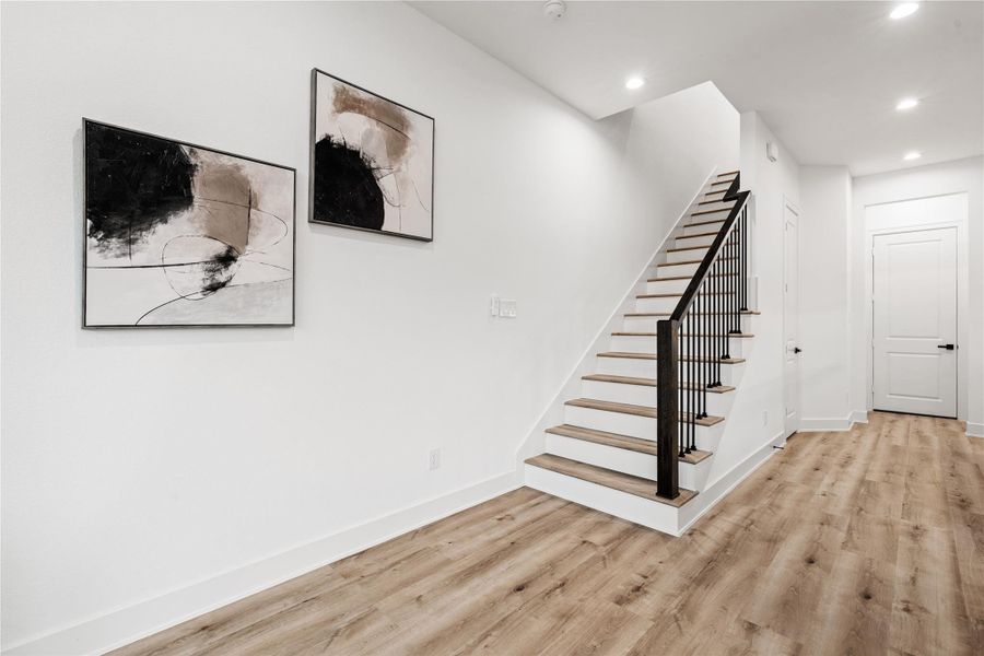 A sculptural focal point in its own right, the stairway pairs sleek black railings with oak-colored treads to create a sense of upward rhythm and architectural grace. Every step reflects Nima Homes’ mastery of proportion and flow—where form becomes function and movement feels artfully designed.