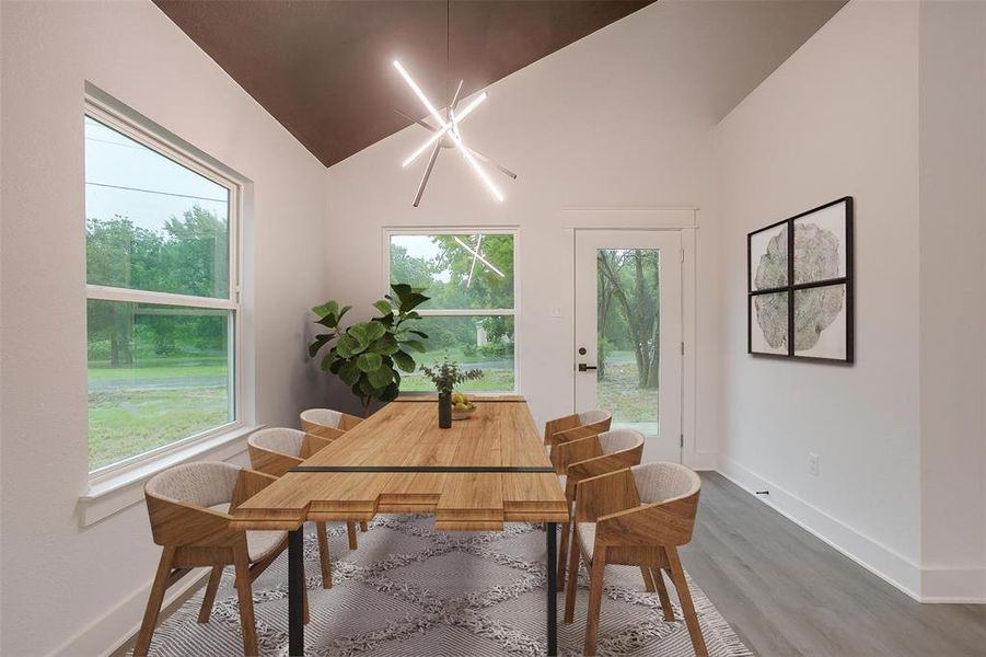 Dining space featuring wood finished floors, plenty of natural light, and vaulted ceiling
