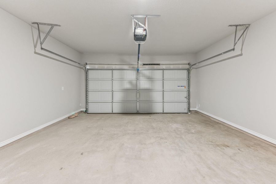 Garage with baseboards and a garage door opener Garage with baseboards and a garage door opener