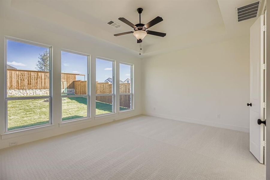 Unfurnished room with light carpet, a raised ceiling, and ceiling fan Unfurnished room with light carpet, a raised ceiling, and ceiling fan