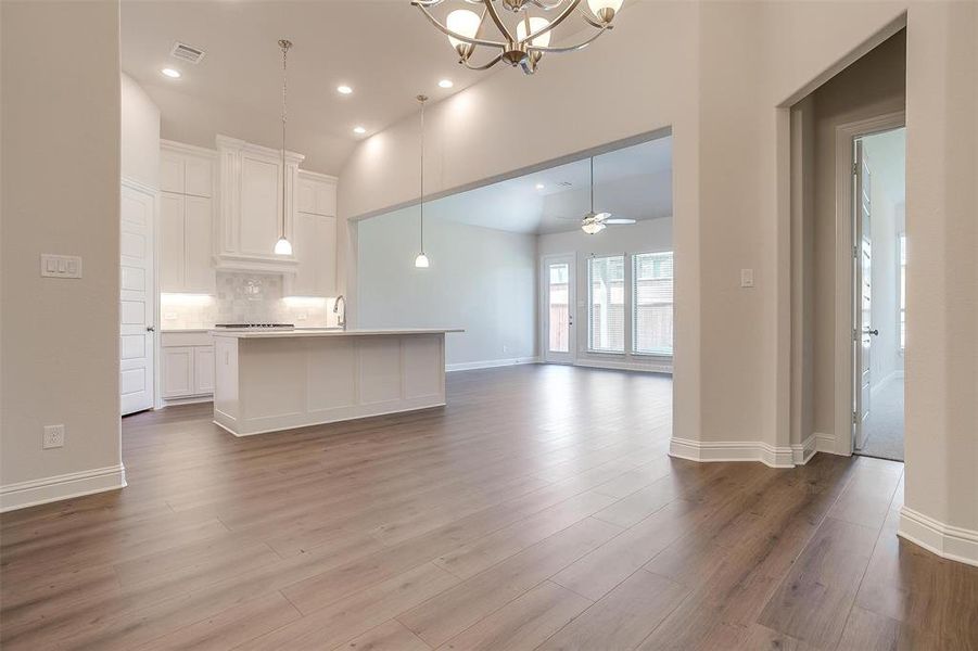 Kitchen featuring white cabinets, a kitchen island with sink, hardwood / wood-style floors, and tasteful backsplash