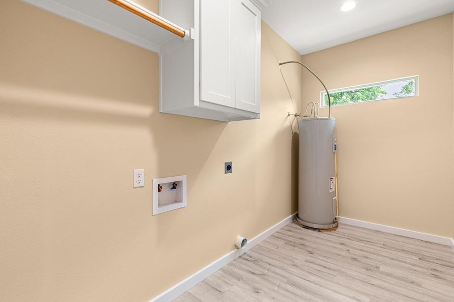 Laundry room with hookup for an electric dryer, electric water heater, cabinet space, light wood-type flooring, and washer hookup